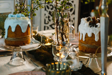 Easter cakes, flowering cherry branches, burning candles, glasses of green glass