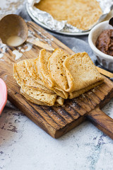 Baked crispy tasty crepes or thin pancakes and crepes dough. Ingredients on table. Vegan dessert. Homemade chocolate paste spread.