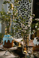 Easter cakes, flowering cherry branches, burning candles, glasses of green glass