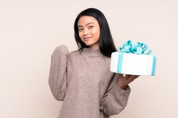 Teenager Asian girl holding a big cake isolated on beige background pointing to the side to present a product