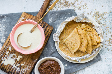 Baked crispy tasty crepes or thin pancakes and crepes dough. Ingredients on table. Vegan dessert. Homemade chocolate paste spread.