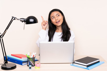 Student asian girl in a workplace with a laptop isolated on beige background intending to realizes the solution while lifting a finger up