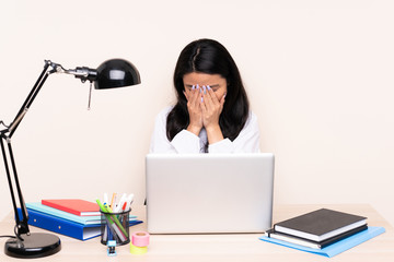 Student asian girl in a workplace with a laptop isolated on beige background with tired and sick expression