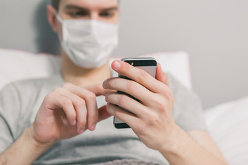 Young man sits on the phone in bed