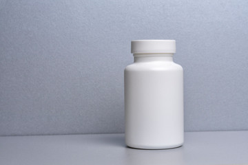1 white jar for medicines and vitamins and dietary supplements without a name are on a gray shelf. copy space to the left. layout for a pharmacy, a store