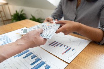 Business woman receiving money from the opposite person.