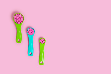 Colorful blue and pink tablets in colored plastic round spoons. Pills, oncept of medicine.