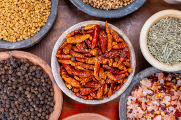 Indian spices collection, dried colorful condiment, nuts, pods and seeds and another spices in clay bowls