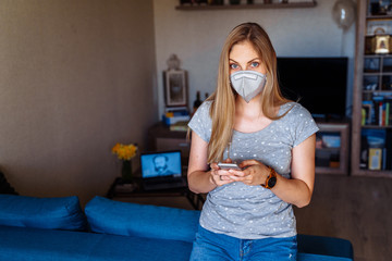 Beautiful girl reading news on the phone on the coronavirus epidemic and calling her friends. She...