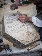 Stonemason carves and shapes the stone with a wooden hammer and chisel.