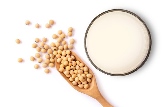 Closeup soy beans in wooden bowl and glass of soy milk isolated on white background. Top view. Flat lay.