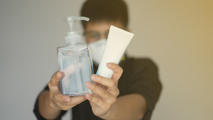 Close up the man holding clear pump liquid alcohol, tube alcohol, ntiseptic for sanitize wearing face hygienic mask, N95 mask for prevention global covid-19 virus pandemic. He chest pain hand protect 