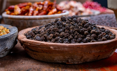 Indian spices collection, dried black peppercorns  and another spices in clay bowls