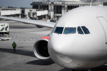 Big commercial airliner at a gate at an airport. Front of a big jet airplane manouvering in the taxiway, pilots seen through the windscreen.