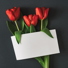 Creative flat lay composition with paper card note and spring flowers. Realistic aesthetic look. Contemporary style.