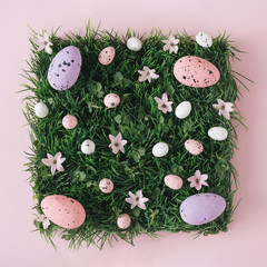 Creative flat lay composition with easter eggs and natural grass and flowers.Pastel colors and soft shadows. Realistic aesthetic look pattern. Contemporary style.