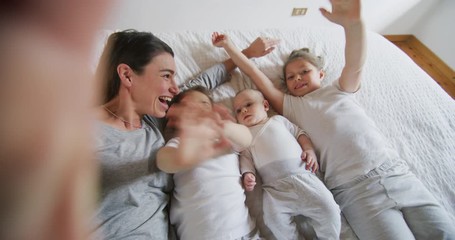 Authentic shot of happy mother with her kids are making a selfie or video call to father or relatives in a bed. Concept of technology, new generation,family, connection, parenthood, authenticity - Powered by Adobe