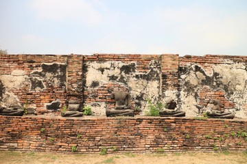 ancient temple with ruined buddha statue and brown brick wall in Ayutthaya, Thailand