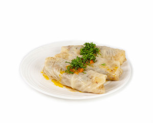 Cabbage rolls in a white plate sprinkled with chopped fresh dill on a white background
