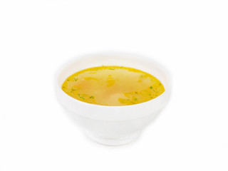 Bowl of golden broth with chopped herbs on a white background side view