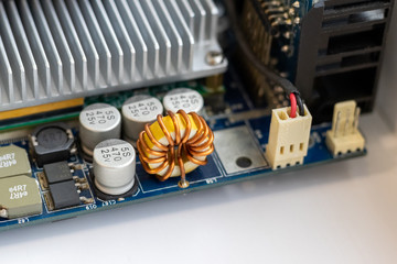 Part of a computer motherboard with capacitors, a transformer and a cooling radiator. Selective...