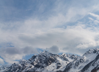 Peaks of snow-capped mountains against the blue sky with clouds