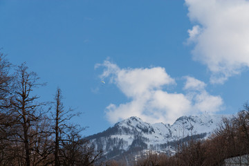 Peaks of snow-capped mountains against the blue sky with clouds