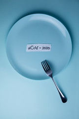 The inscription ncov-2020 on an empty blue plate on a blue background