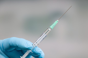 Close up of doctor's hand in medical gloves holding a syringe with serum