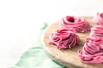 Fresh Hand made beetroot pasta on wooden cutting board. Raw purple spaghetti, fettuccine.