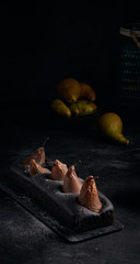 Vegan brownie chocolate loaf cake with pear autumn homemade baked pastry dessert gourmet food on black background. Dark and moody style food photo.