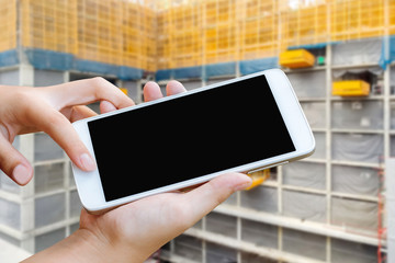 woman hand hold and touch screen smart phone or cellphone over blurred building construction background, 