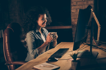 Profile photo of beautiful dark skin business lady look big screen monitor working overtime drink...