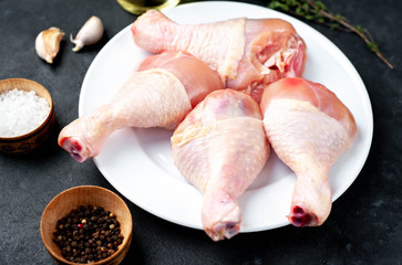 raw chicken legs with spices on a white plate with copy space for your text