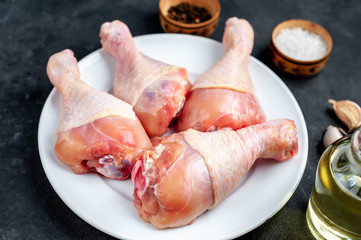 raw chicken legs with spices on a white plate with copy space for your text