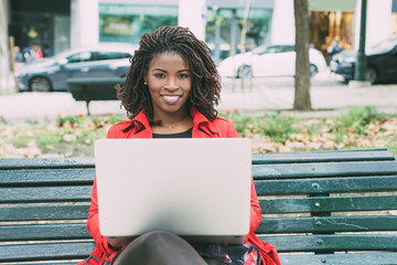 Young woman with laptop smiling at camera. Beautiful happy young African American woman using...