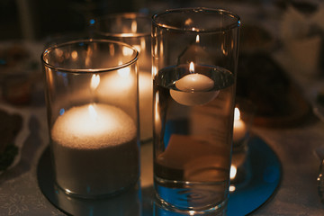 glass of water and candle on black background