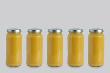 Five cans of canned apple puree in glass jar on gray background.