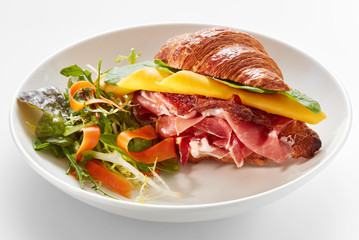 croissant sandwich with jamon and salad in plate
