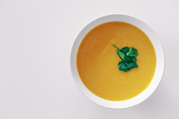 Homemade pumpkin soup with greens on a white background