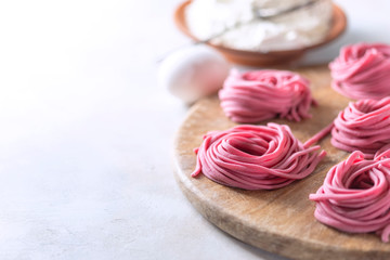 Fresh Hand made beetroot pasta on wooden cutting board. Raw purple spaghetti, fettuccine.