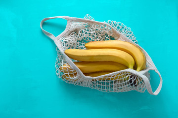 top view string bag full of bananas on a bright blue background
