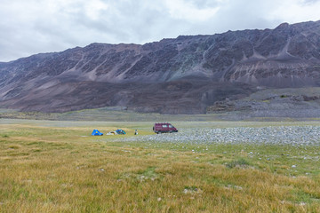 Tourists camping in Mongolian hills. Three tents under the open cloudy sky.