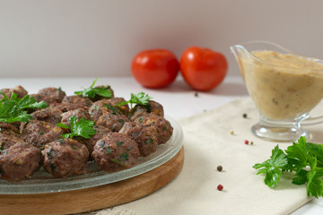 Homemade fried meatballs with herbs on a transparent plate and a wooden cutting board on a white background. Swedish traditional cuisine.