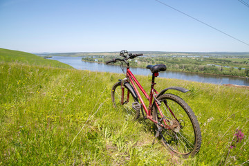 Fototapeta na wymiar mountain bike on the high bank of the river Kama, view of the river Kama and water meadows