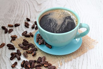 cup of coffee with beans on wooden background