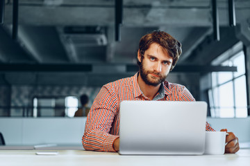 Puzzled thoughtful businessman sitting at his working table in an office. Business concept