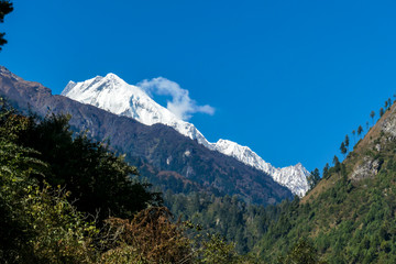 View on Himalayas, Annapurna Circuit Trek, Nepal. Early morning in the mountains. Lower parts of the mountains covered in shadow, high snow caped mountains peaks catching the first beams of sunlight