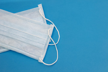 Two medical disposable masks on a blue background with an empty space for text, copy space, flat lay, top view