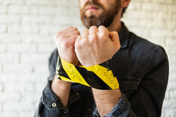Man hands tied during Corona virus quarantine, signal tape marked with COVID-19 inscription